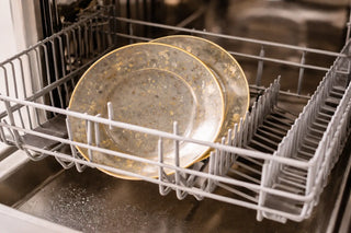 Handcrafted fused glass plate placed safely in a dishwasher rack for cleaning